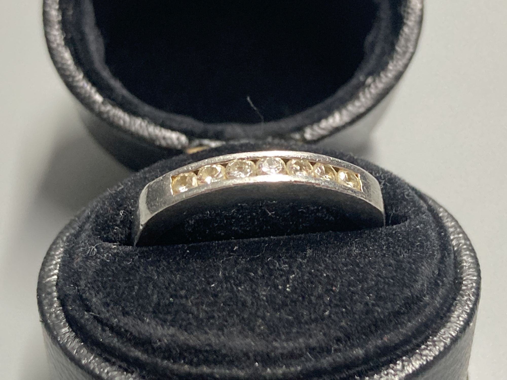 A modern platinum and channel set seven stone diamond half hoop ring, size K/L, gross 4 grams.